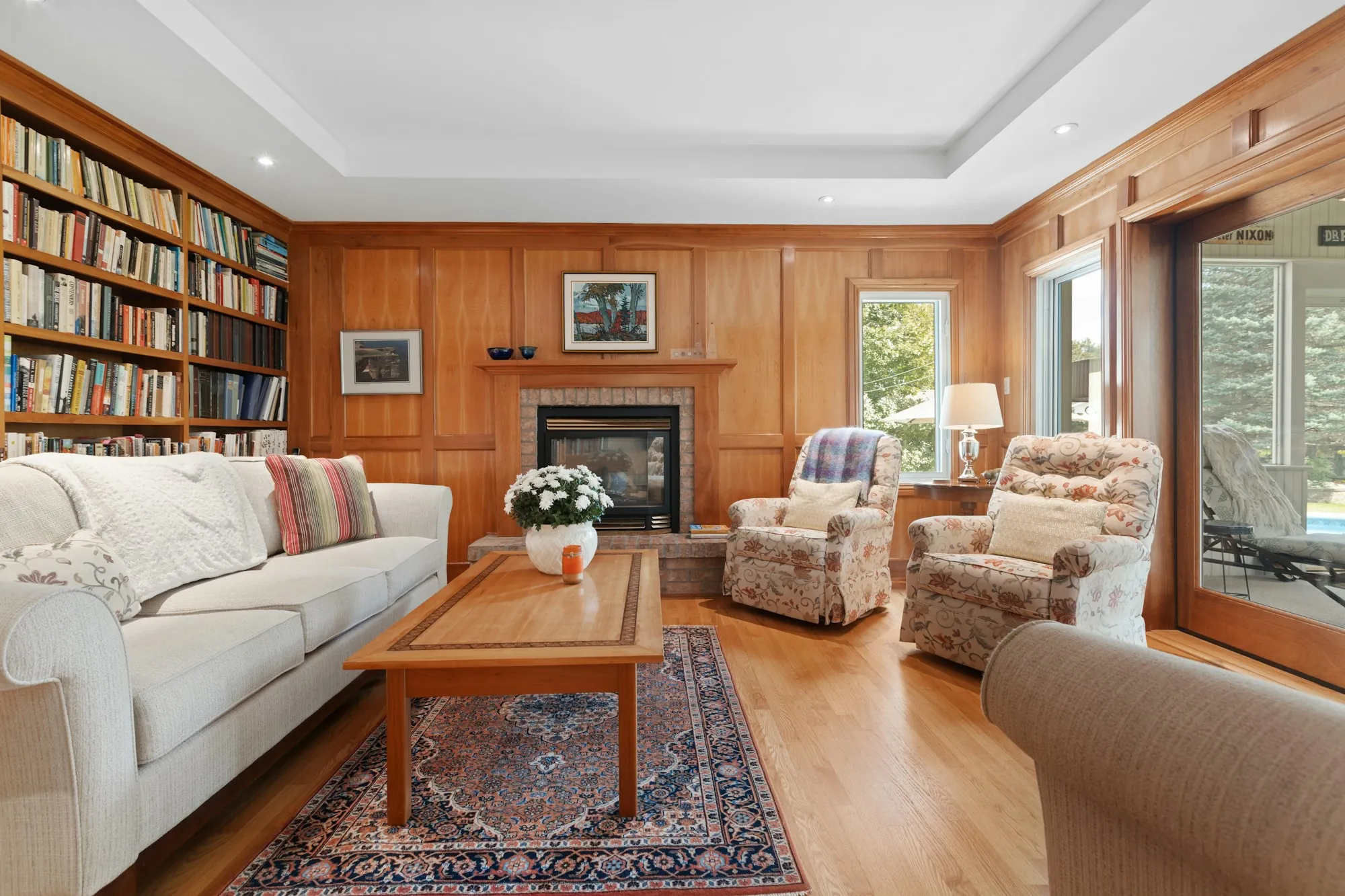 Wood-paneled living room with built-in bookshelves and a fireplace